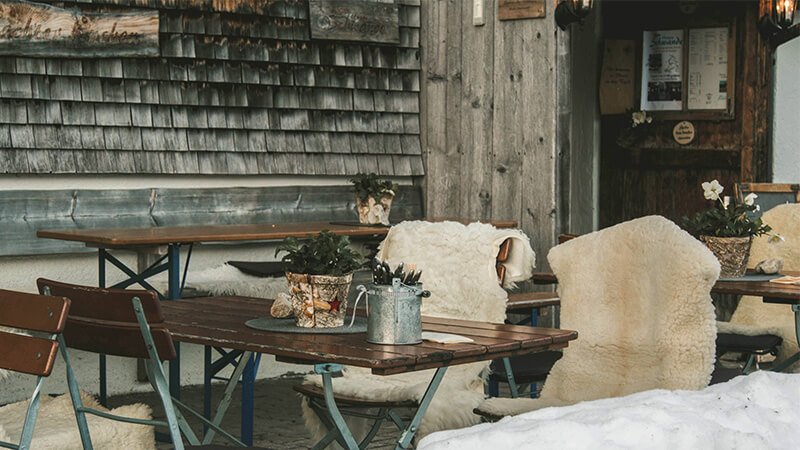 a ski season job, a mountain restaurant with outside wooden tables and fur rugs on the chairs.