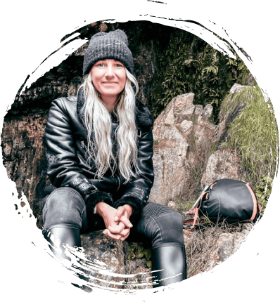 Teri-Anne, long blonde hair, dressed in black sat on a rock
