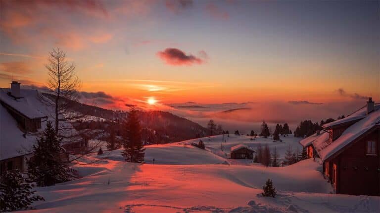 sunsetting over a snowy mountain village in a ski resort