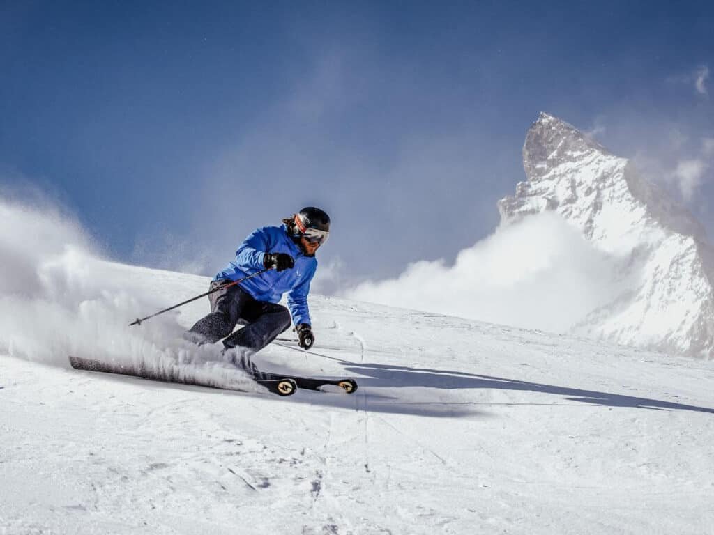 A man carving turns on his skis in front of the Matterhorn.