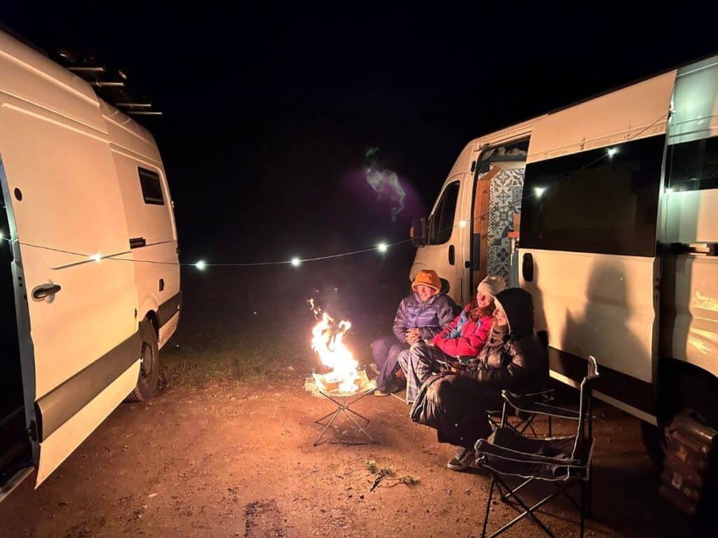 2 Campervans parked up in the woods at night with a pop up fire pit in Scotland.
