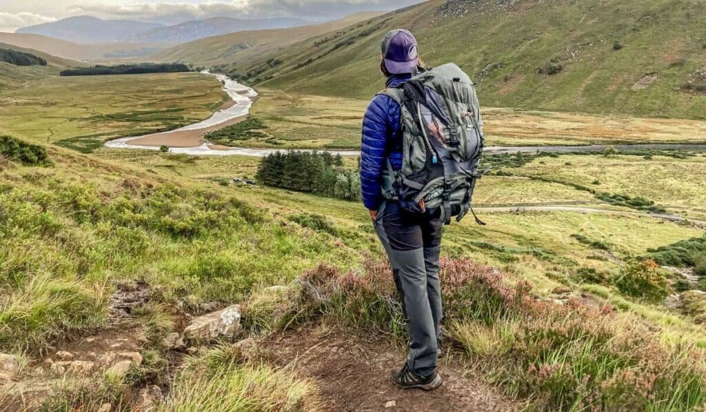 A hiker on their way down from Ben Hope, carrying a big backpack, looking out at the path below. 