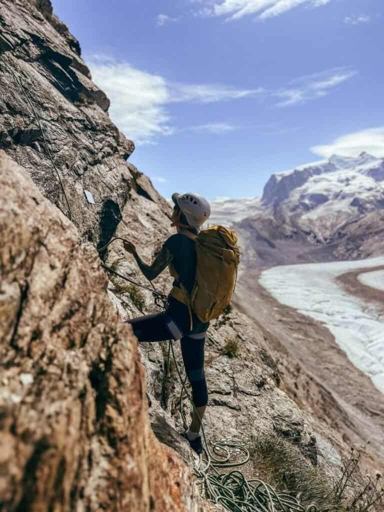Woman belaying on a sport climb on the Riffelhorn, infornt of the Gorner Glacier in Zermatt during October. Sport climbing is a great reason to visit Zermatt.