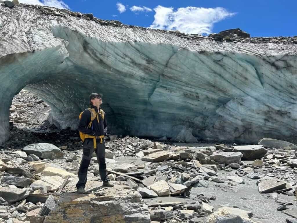 Man stood infront of huge glacial ice formation in Zermatt, Switzerland. A great reason why Zermatt is worth visiting in the summer.